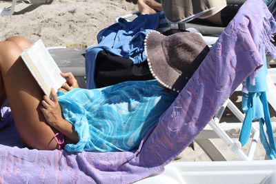 Rear view of woman sitting on book at beach