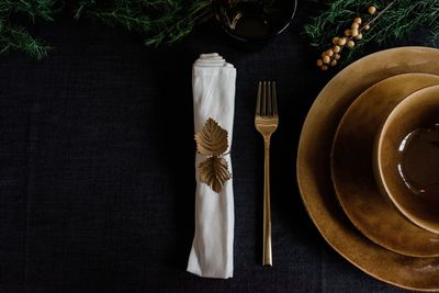 Gold napkin holder, plates and fork on a decorated table setting