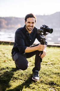 Portrait of young man photographing on field