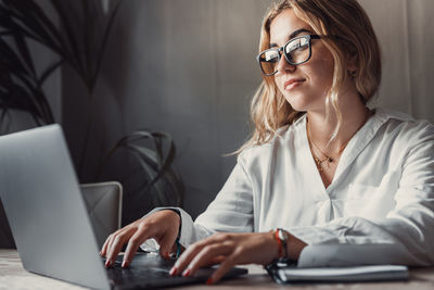 Portrait of young woman using laptop at desk in office