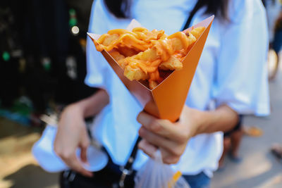 Close up french fried melted cheddar cheese in small cardboard holder