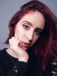 Close-up portrait of young woman against gray background