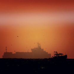 Silhouette built structure against orange sky