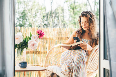 Young woman using mobile phone while sitting at home