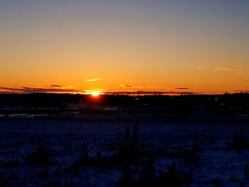 Scenic view of landscape against orange sky during sunset