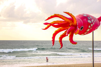 Red umbrella on beach against sky