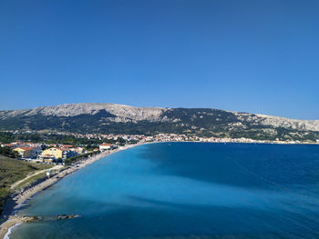 Scenic view of sea and mountains against clear blue sky