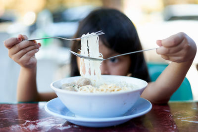 Cute girl eating food in bowl at home