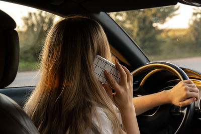 Midsection of woman using mobile phone while sitting in car