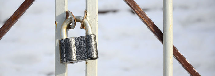 Close-up of padlock hanging on railing against sky