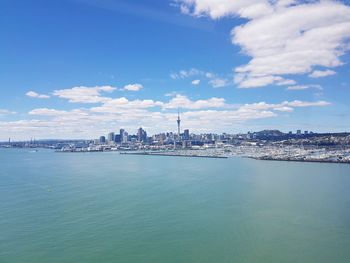 City at waterfront against cloudy sky