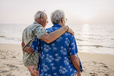 Gay couple with arms around at beach on vacation