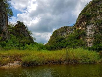 Scenic view of river by trees against sky