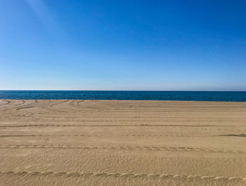 Scenic view of beach against clear blue sky