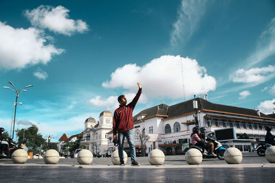 Rear view of man cycling on street against sky