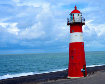 Lighthouse by sea against sky