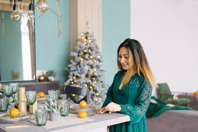 Pretty woman in a turquoise dress serves a festive table for the holiday