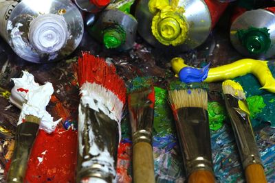 High angle view of colorful paintbrushes and paint tubes
