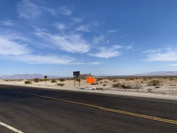 Road by desert against sky