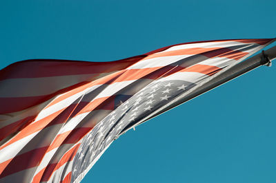 Low angle view of flags against clear blue sky