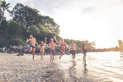 People playing on beach against sky