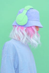 Woman wearing hat standing against colored background