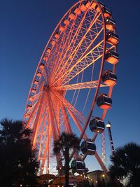 Low angle view of orange ferris wheel against clear blue sky
