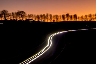 Light trails on road against sky at night