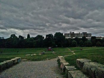 Trees on field against cloudy sky