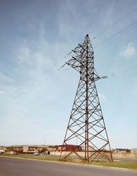 Low angle view of electricity pylon on field against sky