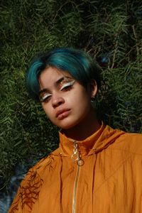 Portrait of young woman standing against plants