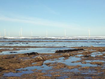 Windmills in sea against sky