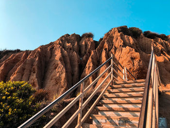 Staircase leading towards mountain against clear blue sky