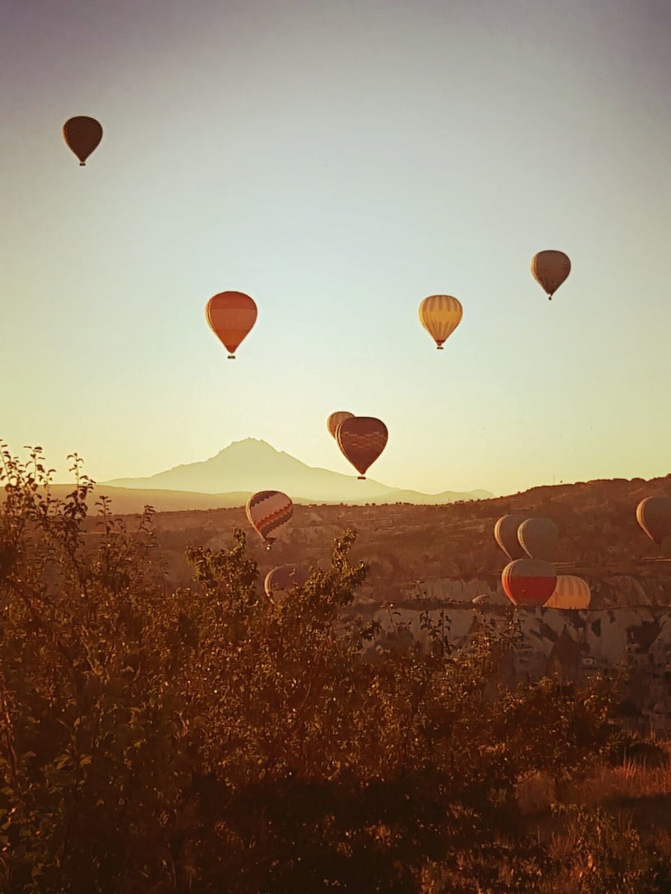 air vehicle, hot air balloon, transportation, balloon, sky, mode of transportation, nature, mid-air, landscape, flying, adventure, environment, travel, scenics - nature, no people, land, beauty in nature, mountain, sun, tranquil scene, freedom, outdoors, ballooning festival