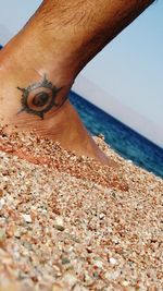 Low section of man at beach against sky