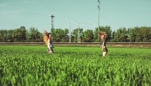 Friends enjoying on grassy field against sky