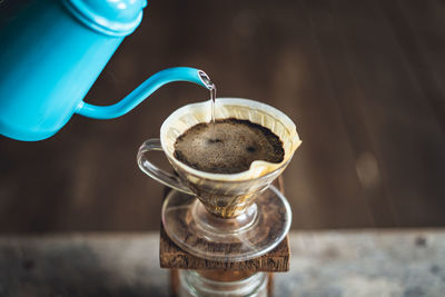 Black coffee pouring in jar on table