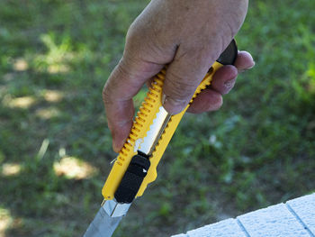 Close-up of hand holding yellow utility knife