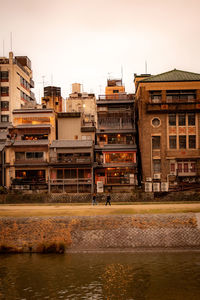 Buildings by river against clear sky