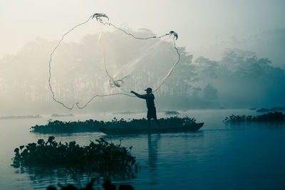 Man in lake against sky