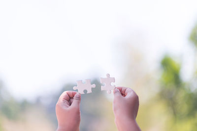 Close-up of person holding hands against sky