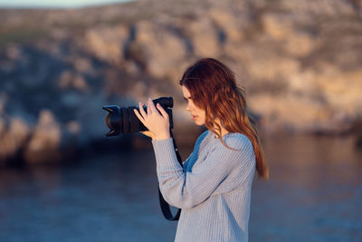 Woman photographing against sky