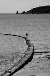 Man in sea against sky during sunset
