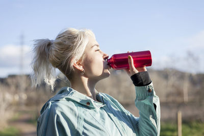 Portrait of woman drinking water from sunglasses