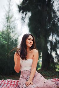 Portrait of a smiling young woman against trees