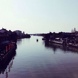 Scenic view of houses by river against clear sky