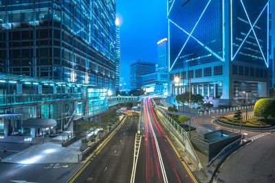 Light trails on road amidst buildings in city at night