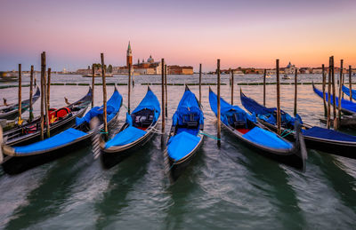 Boats moored at sea against sky during sunset