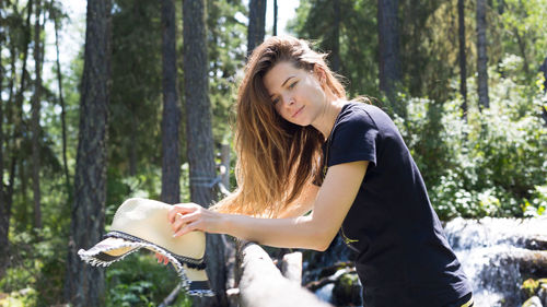 Beautiful young woman standing in forest