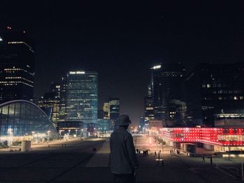 Rear view of woman standing in city at night